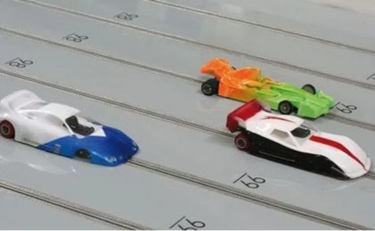 three-toy-racing-scaletrix-cars-on-grey-track-middle-one-winning